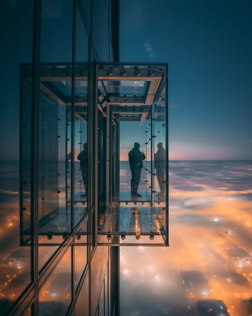 person enjoying the beautiful view of the city on a balcony with glass walls in a tall skyscraper